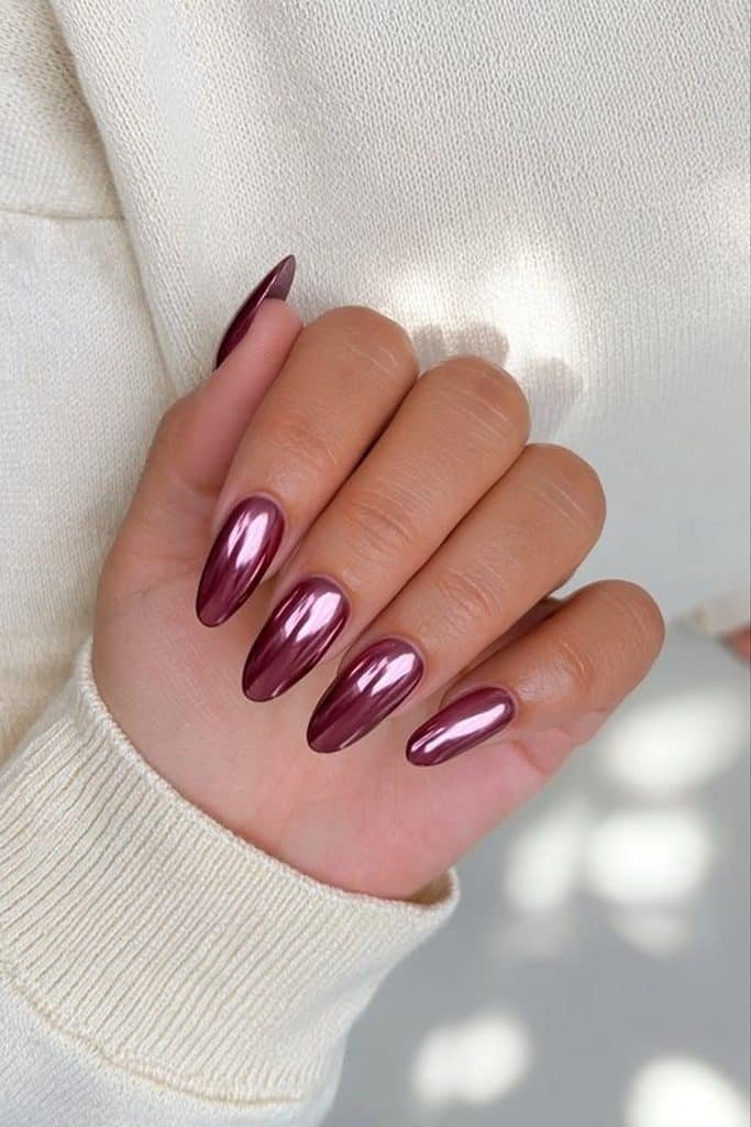 Deep burgundy chrome nails with reflective wine-red metallic shine and ruby highlights