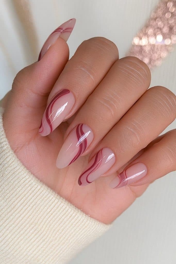 Milky nude nails with flowing burgundy swirls and glossy modern nail art