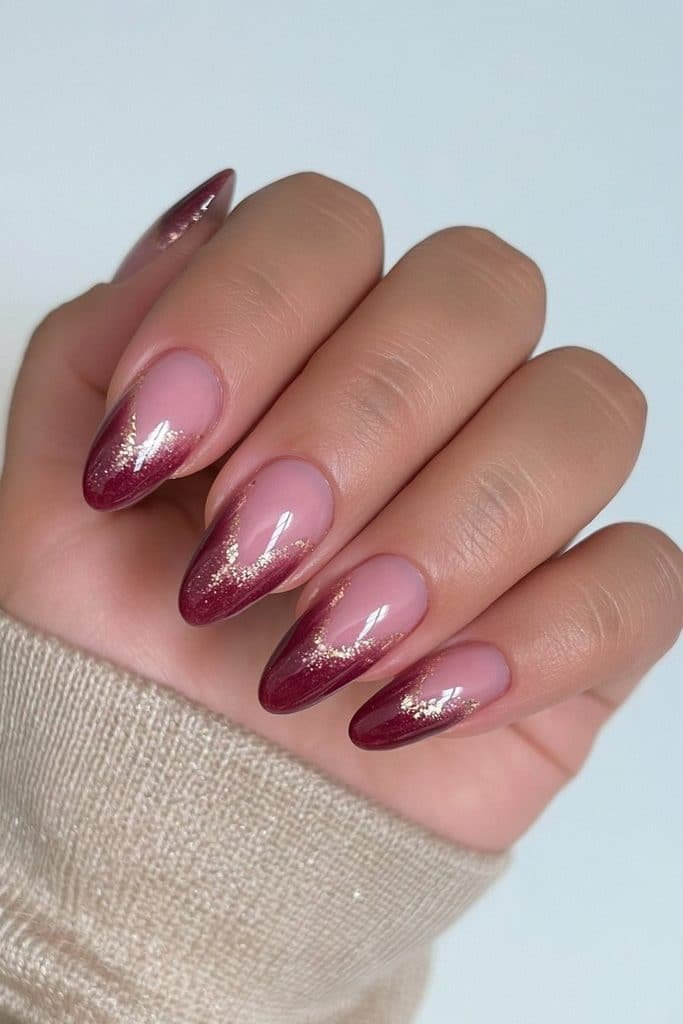 Rich burgundy nails with delicate metallic gold accents and luxurious glossy shine