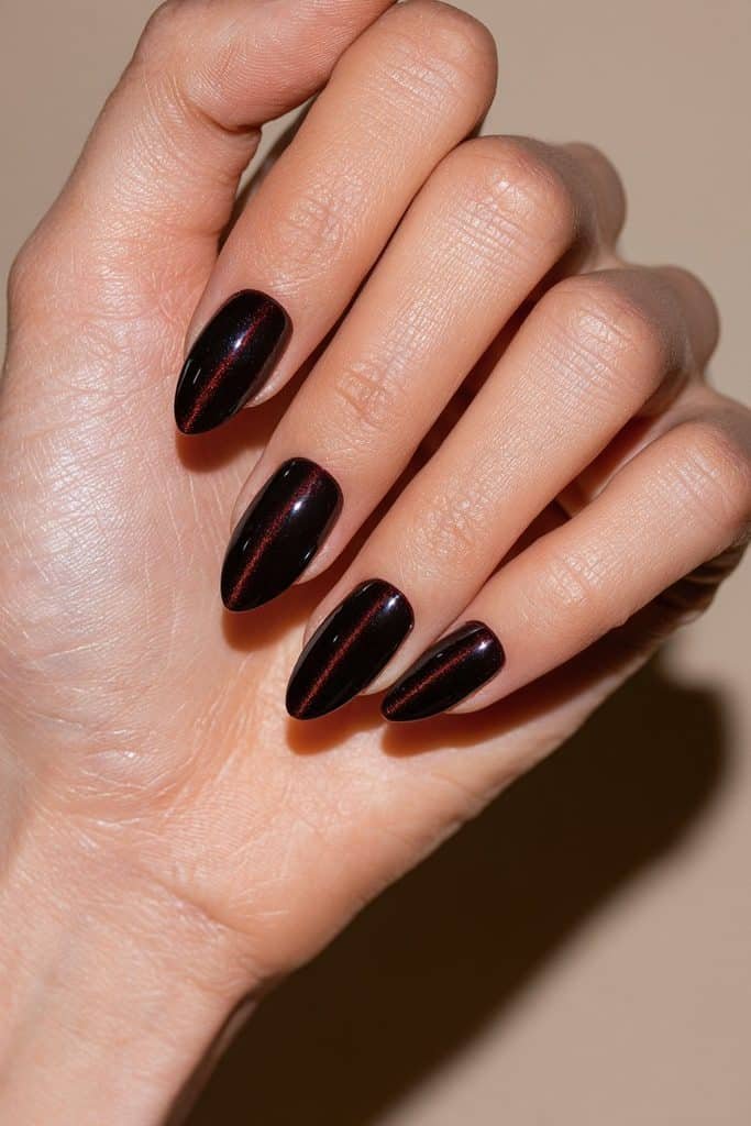 Classic maroon cat eye nails with a luminous ruby-red magnetic streak and glossy deep burgundy finish.