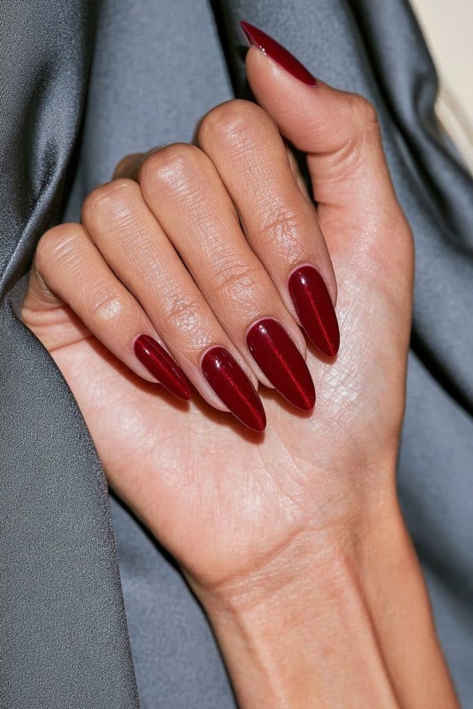 Classic cherry red cat eye nails with glowing ruby magnetic shimmer and a glossy almond-shaped finish.