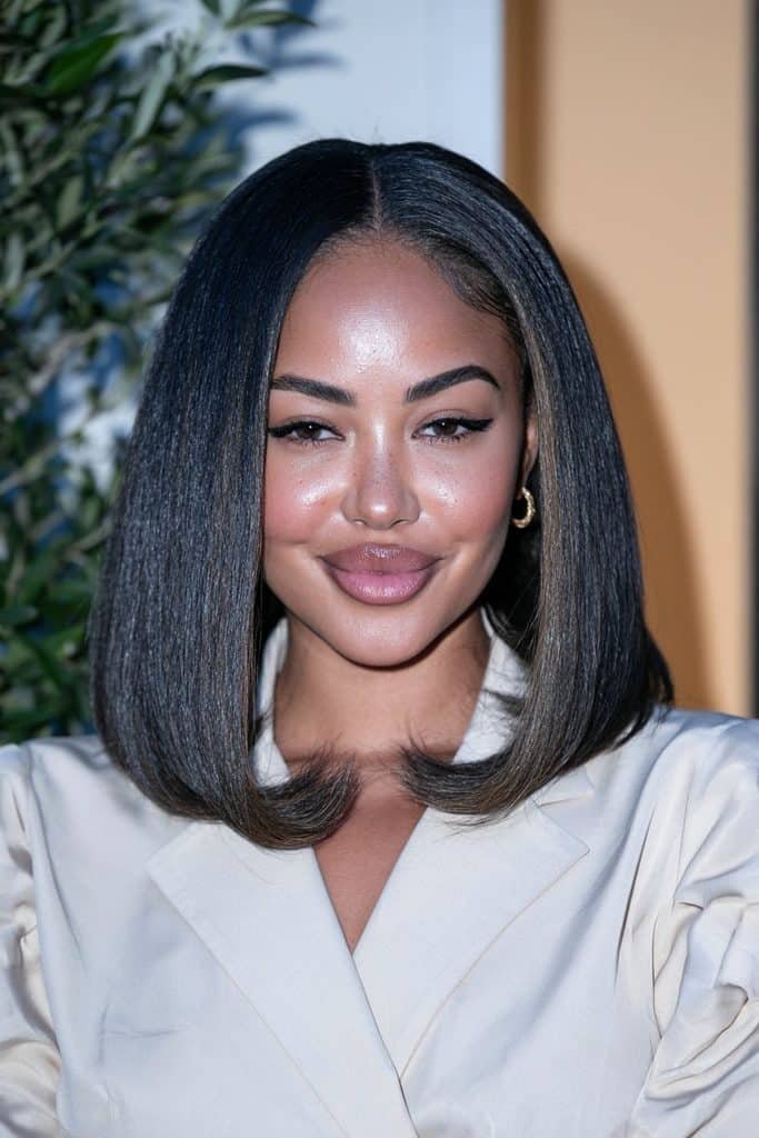 Black woman with a classic silk press flipped bob hairstyle, featuring sleek, shiny black hair and smooth ends curled outward for a polished finish.