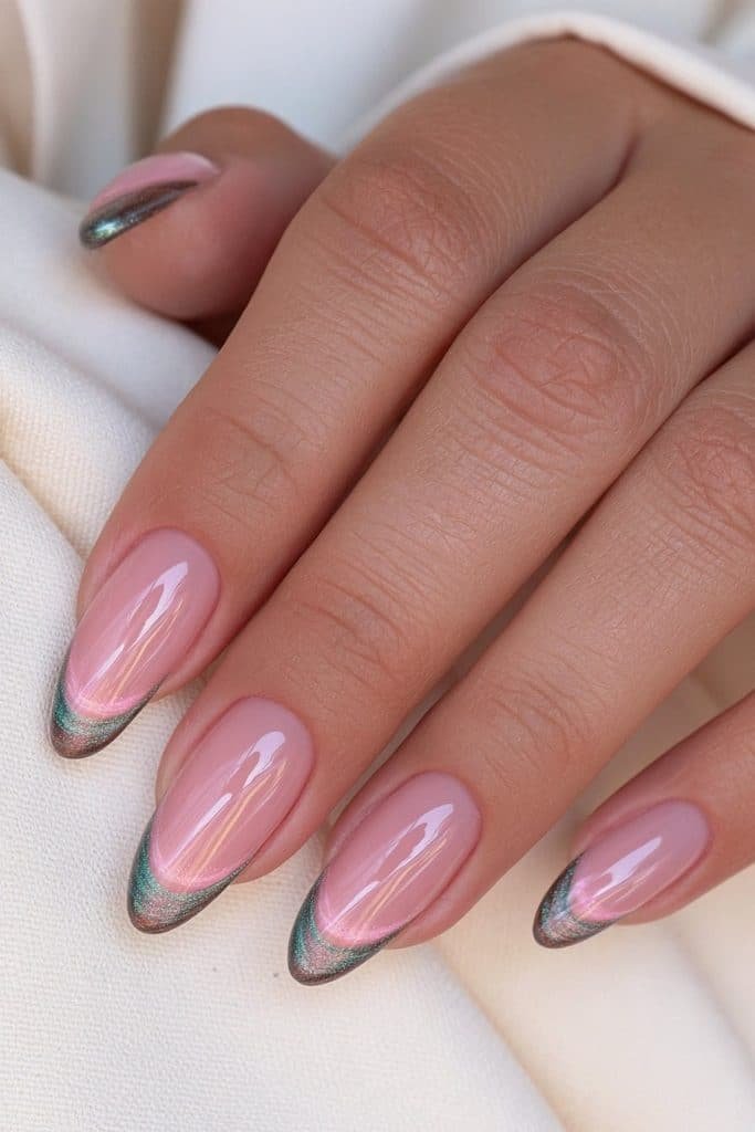 Almond French tip nails with a sheer blush-pink base and glowing dark emerald cat eye tips.