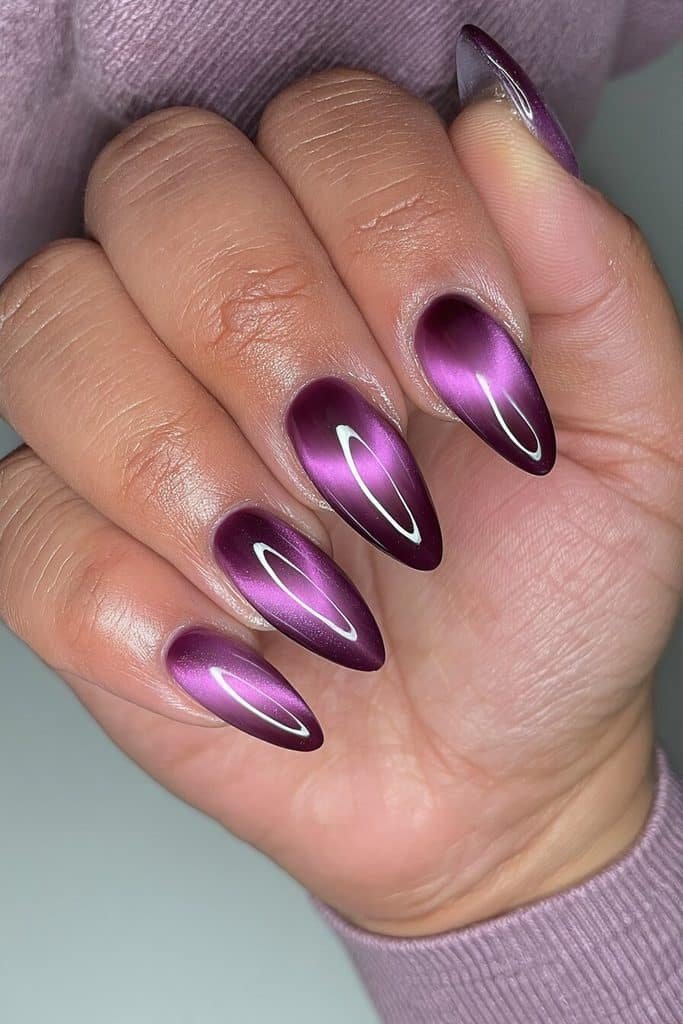 Dark purple cat-eye aura nails with glowing plum centers and soft lilac highlights