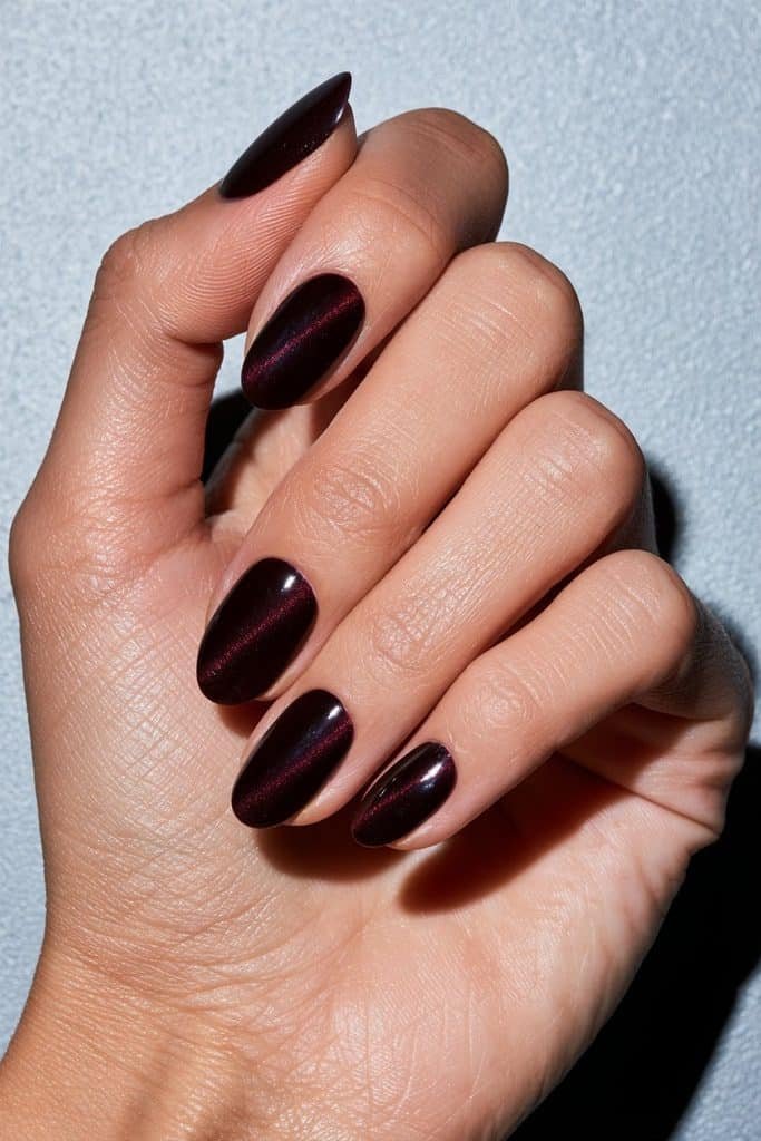 Deep burgundy cat eye nails featuring luminous wine-red magnetic stripes and a glossy oval-almond manicure.