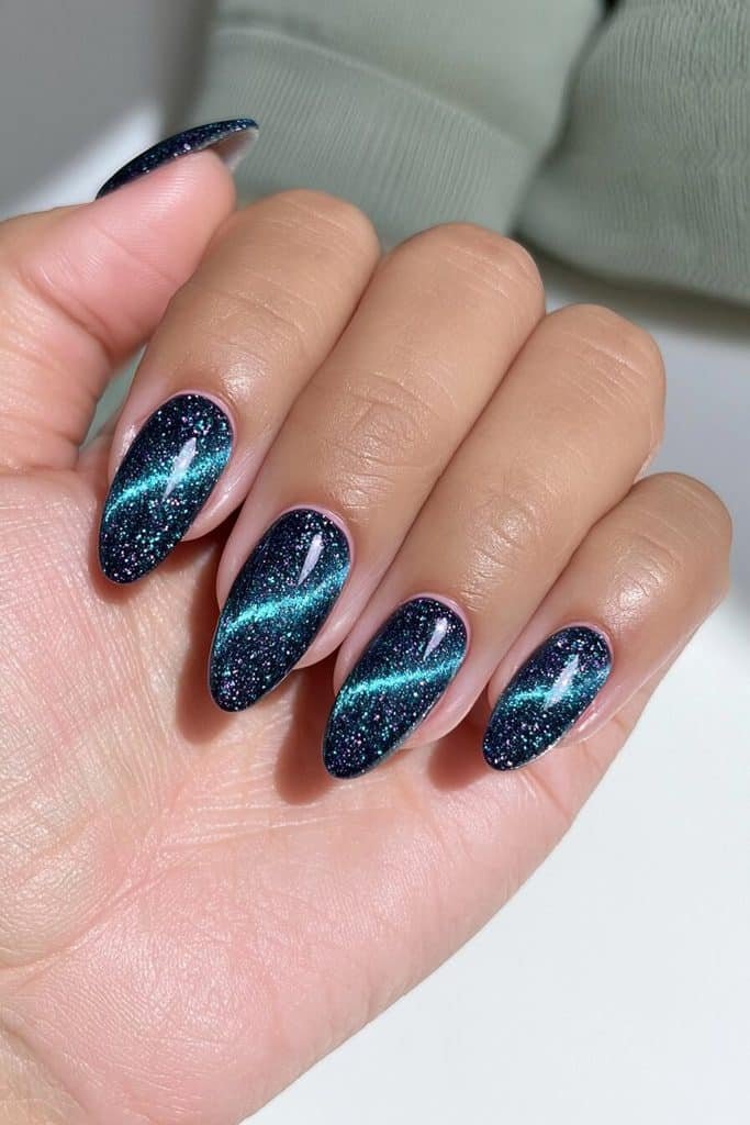 Deep ocean teal-blue cat-eye nails with glowing turquoise bands and subtle petrol-green reflections