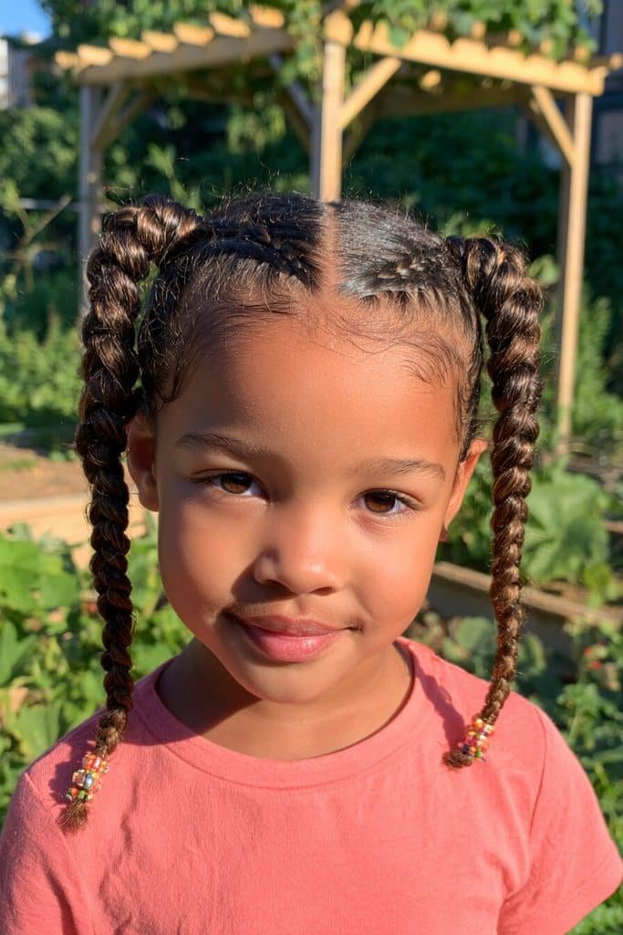 Kids Dutch braids with raised three-dimensional plaits, a center part, and colorful beads at the ends.