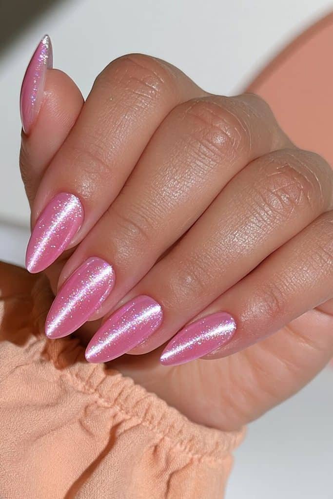 Flamingo pink cat-eye nails with warm coral undertones, glowing rosy bands, and luminous polish