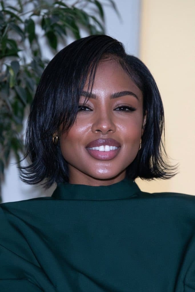 Black woman with a flipped bob and side-swept bangs, featuring smooth black hair, a sweeping fringe, and ends turned outward for a chic look.