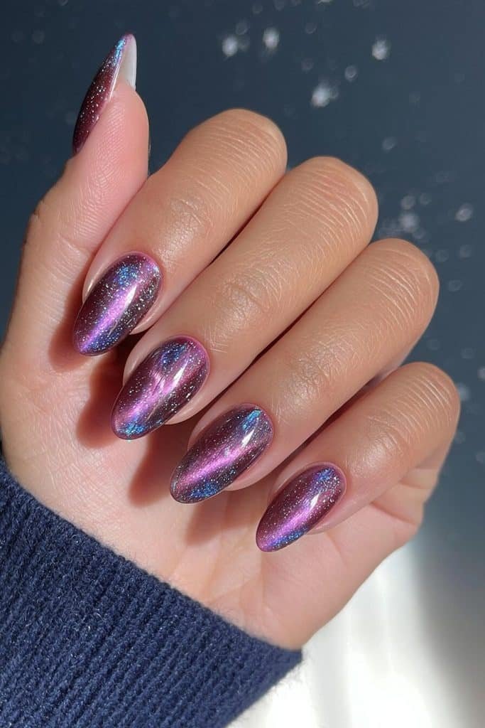 Galaxy purple cat-eye nails with violet nebula streaks, tiny silver stars, and blue shimmer
