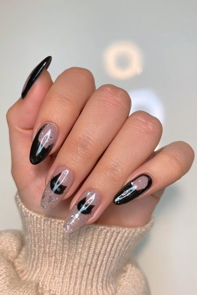 Glossy black cat nails with delicate silhouettes and sparkling silver glitter accents