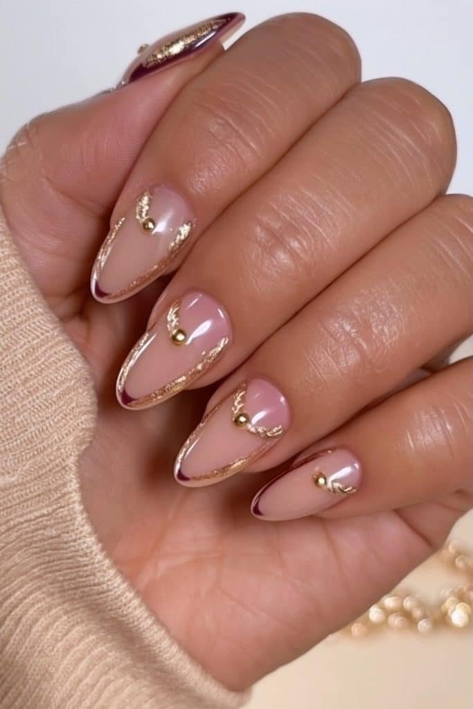 Burgundy and sheer nude nutcracker nails with intricate metallic gold braid details