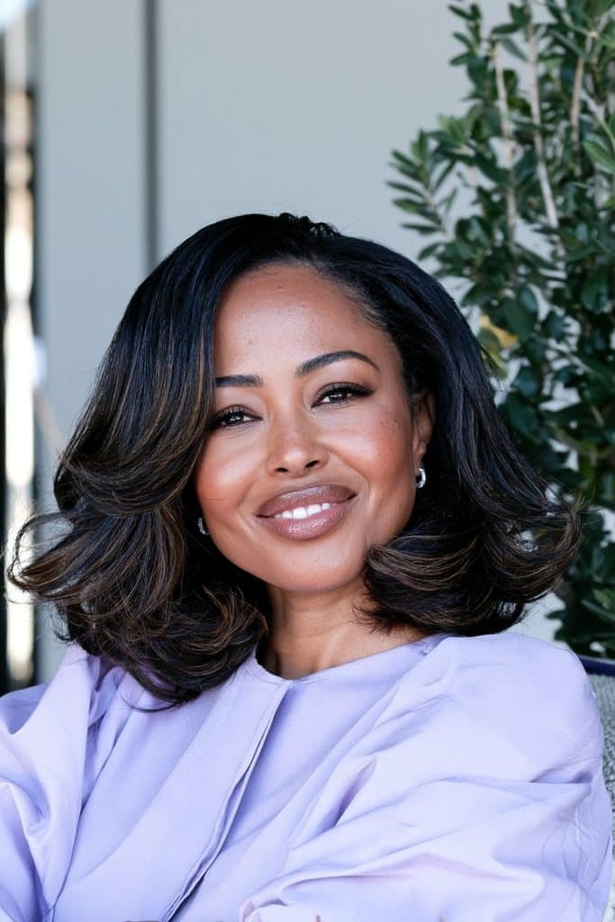 Black woman with a layered flipped bob haircut, featuring soft layers, added movement, and outward-flipped ends for a voluminous finish.