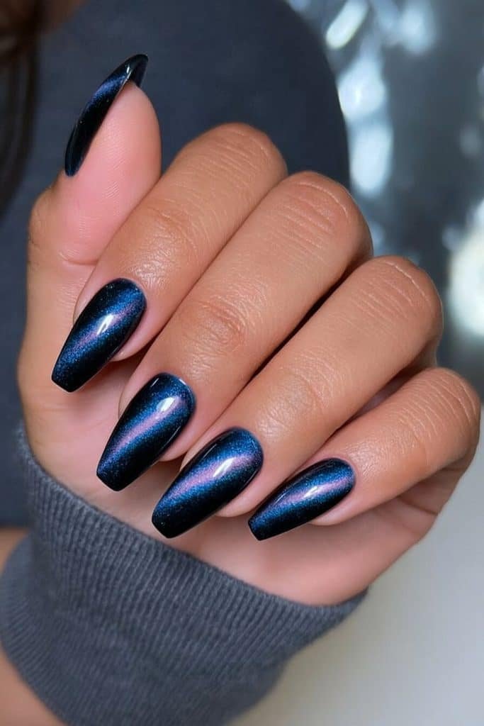 Midnight blue coffin cat-eye nails with tapered sides, squared tips, and brilliant sapphire highlights