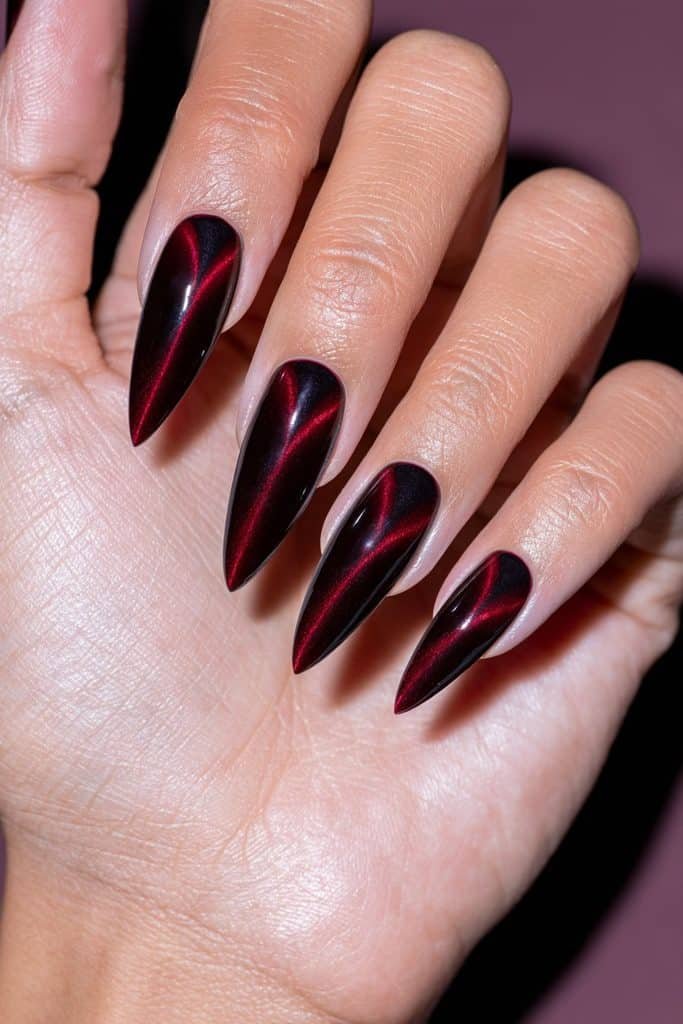Maroon moon halo cat eye nails with glowing ruby-red crescent shapes near the base of each glossy burgundy nail.