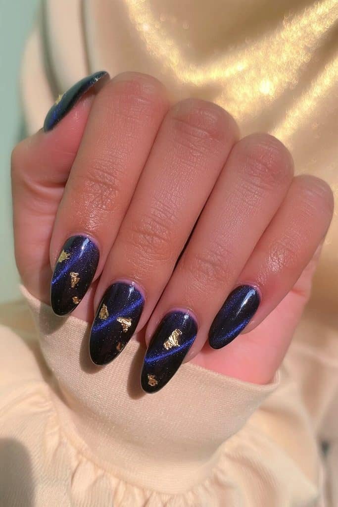 Midnight navy cat-eye nails with luminous cobalt ribbons and delicate gold foil accents