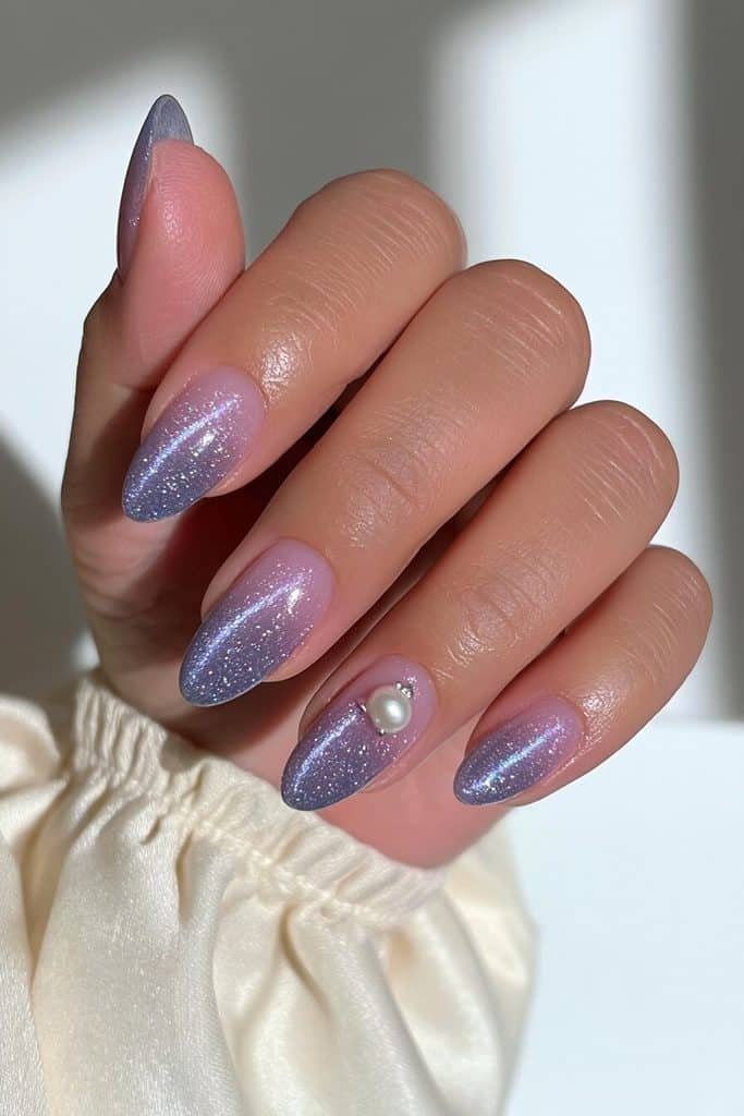 Navy cat-eye nails with glowing sapphire ribbons and an elegant ivory pearl accent