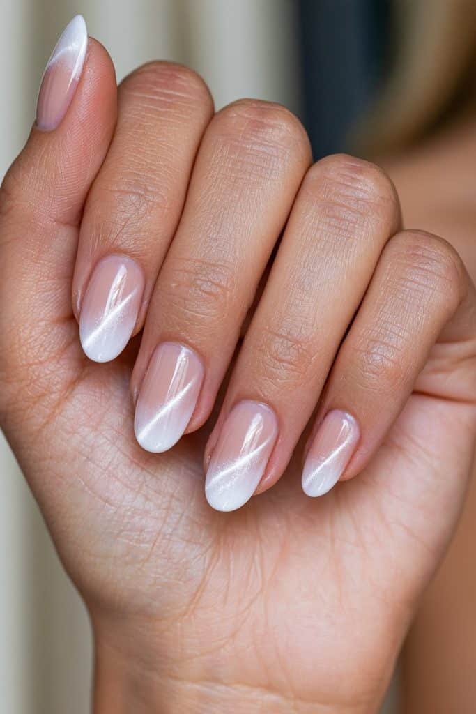 Neutral-to-white ombre cat eye nails with a beige-pink gradient and luminous magnetic reflections