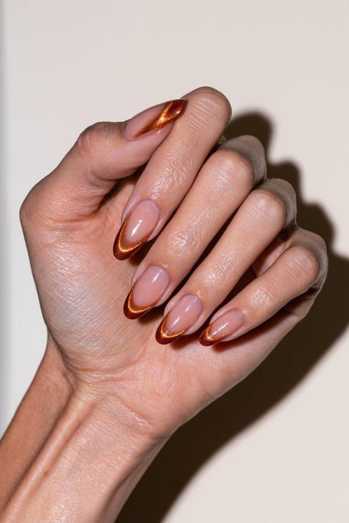 Orange cat eye French tip nails with a clean tip line and reflective magnetic shimmer.