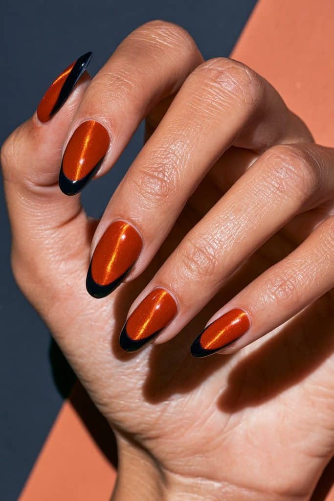 Glowing orange cat eye nails finished with contrasting black tips.
