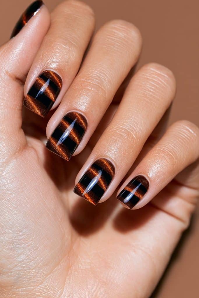 Orange and chocolate brown cat eye nails with a layered, color-blocked magnetic design.