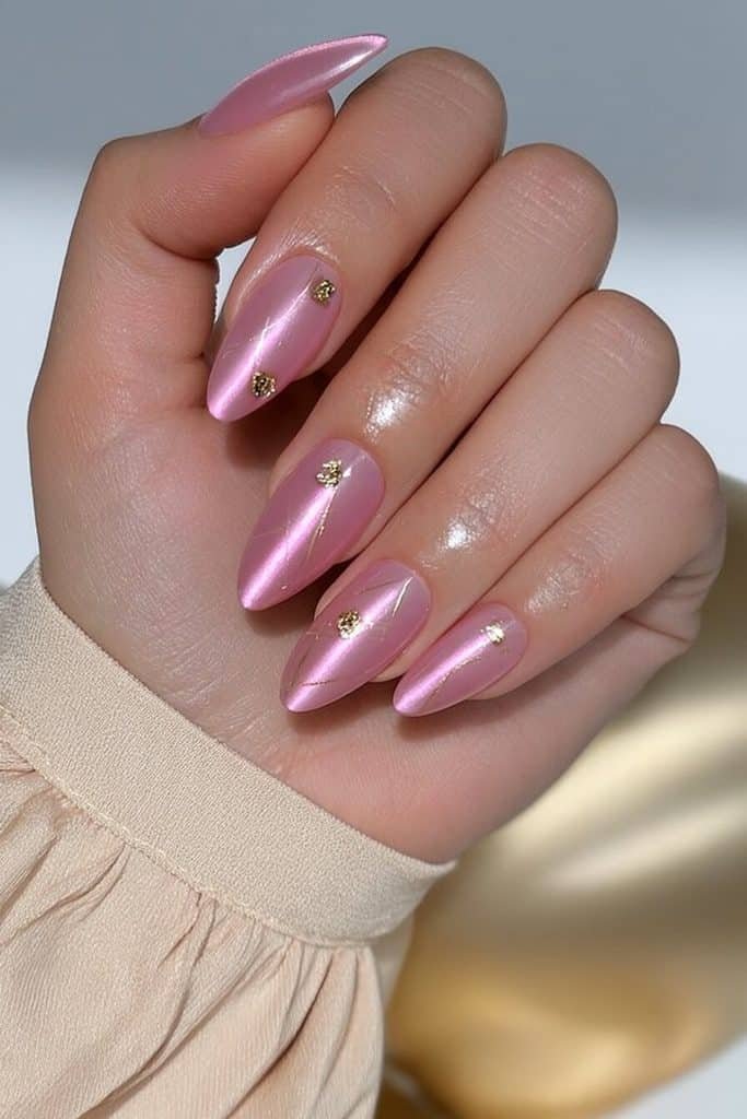 Pink cat-eye nails with luminous rose-pink bands, delicate gold lines, and tiny gold foil accents