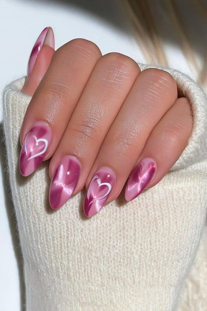 Pink cat-eye nails with glowing baby-pink and rose-pink polish and delicate heart accents