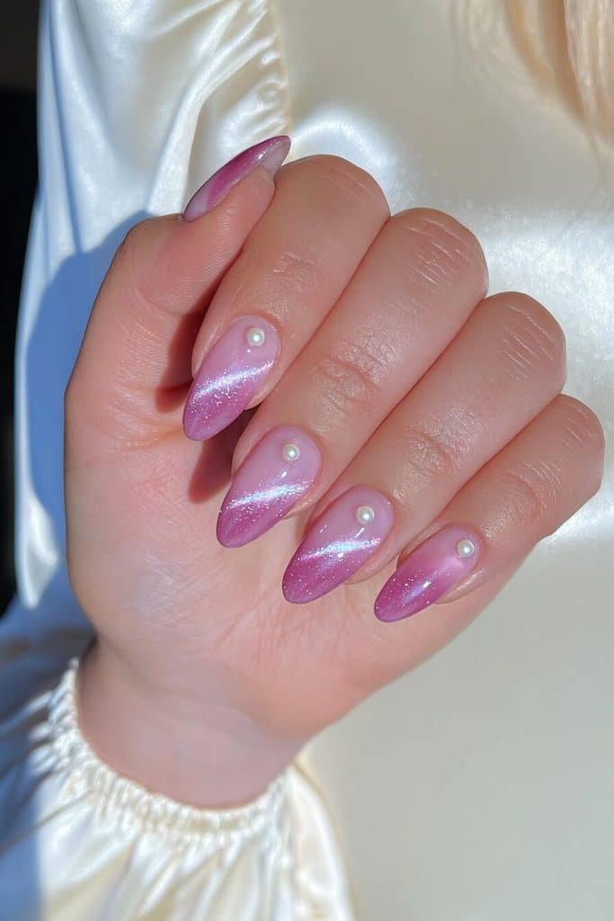 Blush pink cat-eye nails with pearlescent magnetic ribbons and tiny ivory pearl accents near the cuticles