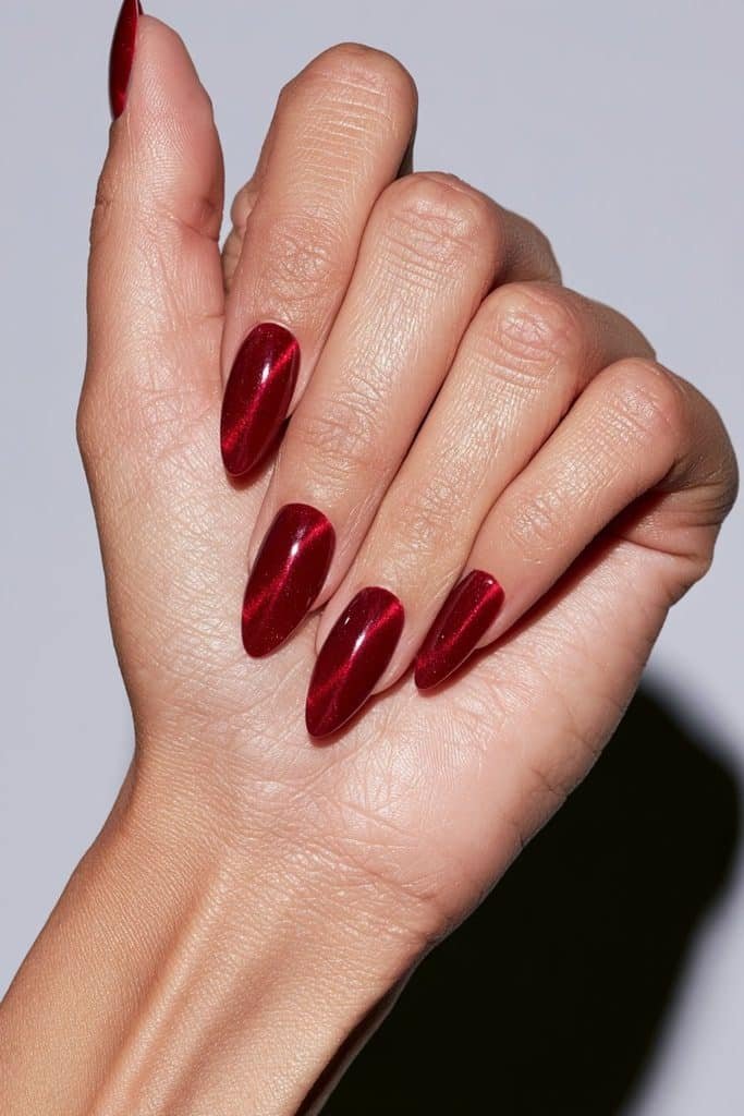 Red cat eye aura nails with luminous ruby centers, fading crimson edges, magnetic shimmer, and a glossy finish.