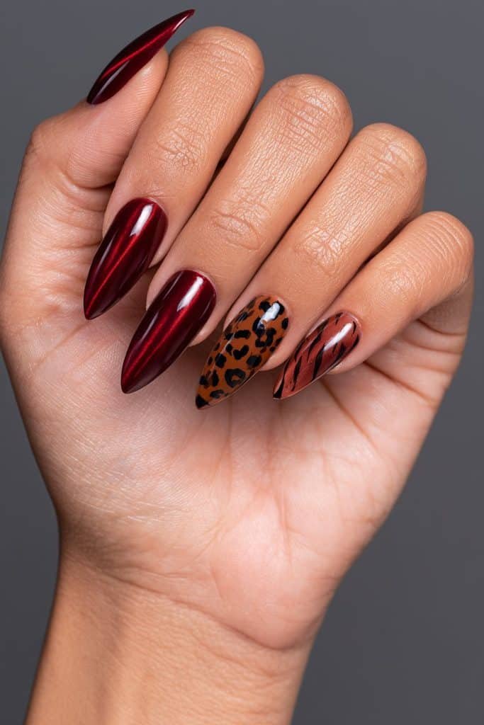 Red cat eye nails with glowing ruby magnetic stripes and leopard-print and tiger-stripe accent nails in warm brown tones.