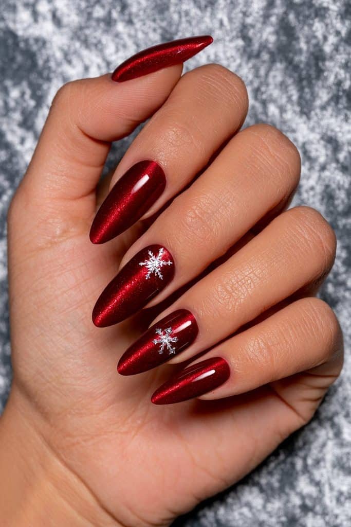 Red cat eye Christmas nails with glowing ruby magnetic stripes, delicate white snowflakes, and tiny silver stars.