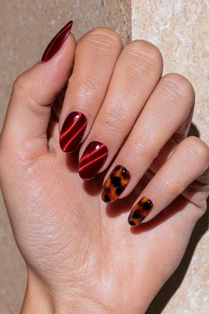 Red cat eye nails with glowing cherry-red magnetic stripes and amber, caramel, and dark brown tortoiseshell accent nails.