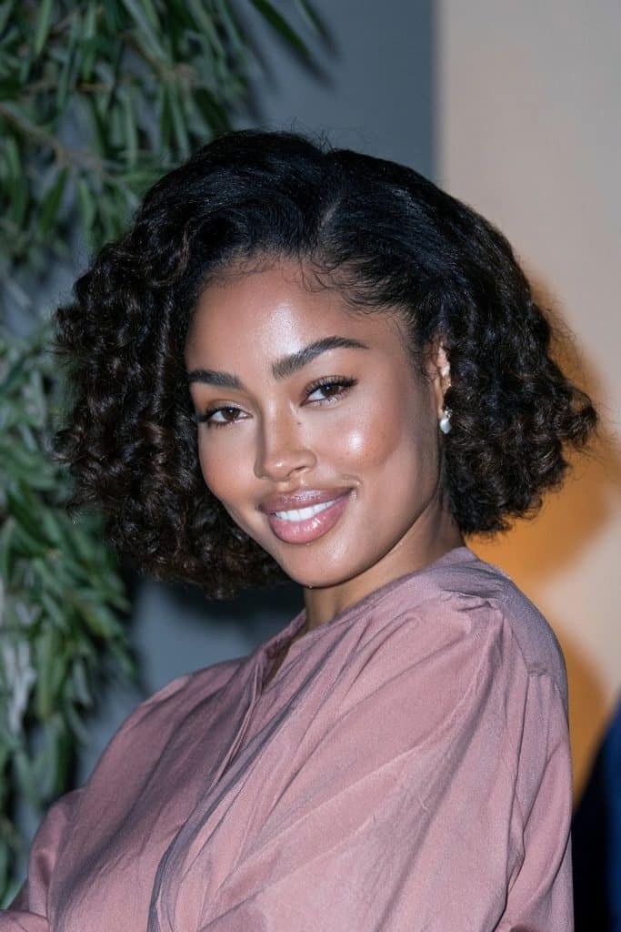 Black woman with a roller-set flipped bob on natural curls, featuring defined curls, rounded volume, and softly flipped ends for a bouncy finish.