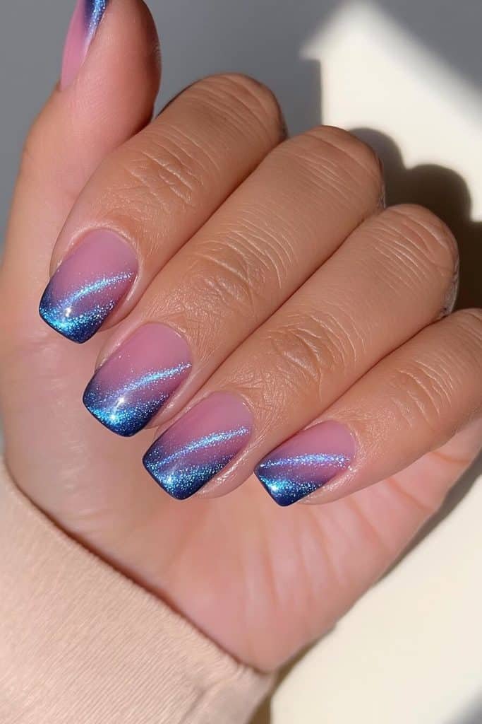 Short sapphire blue cat-eye nails with electric-blue light streaks and a glossy finish