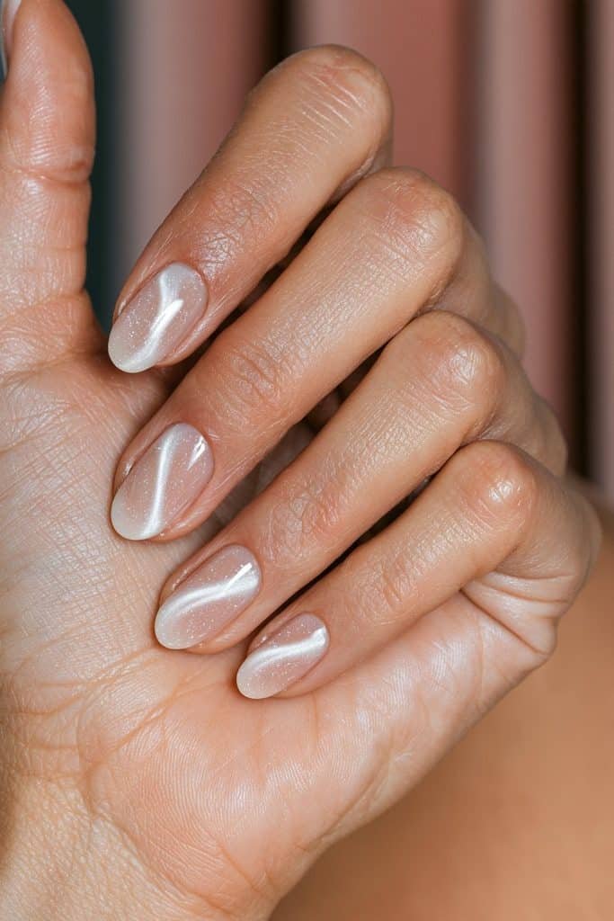 Sheer blush and white cat eye nails with pink undertones and luminous magnetic reflections