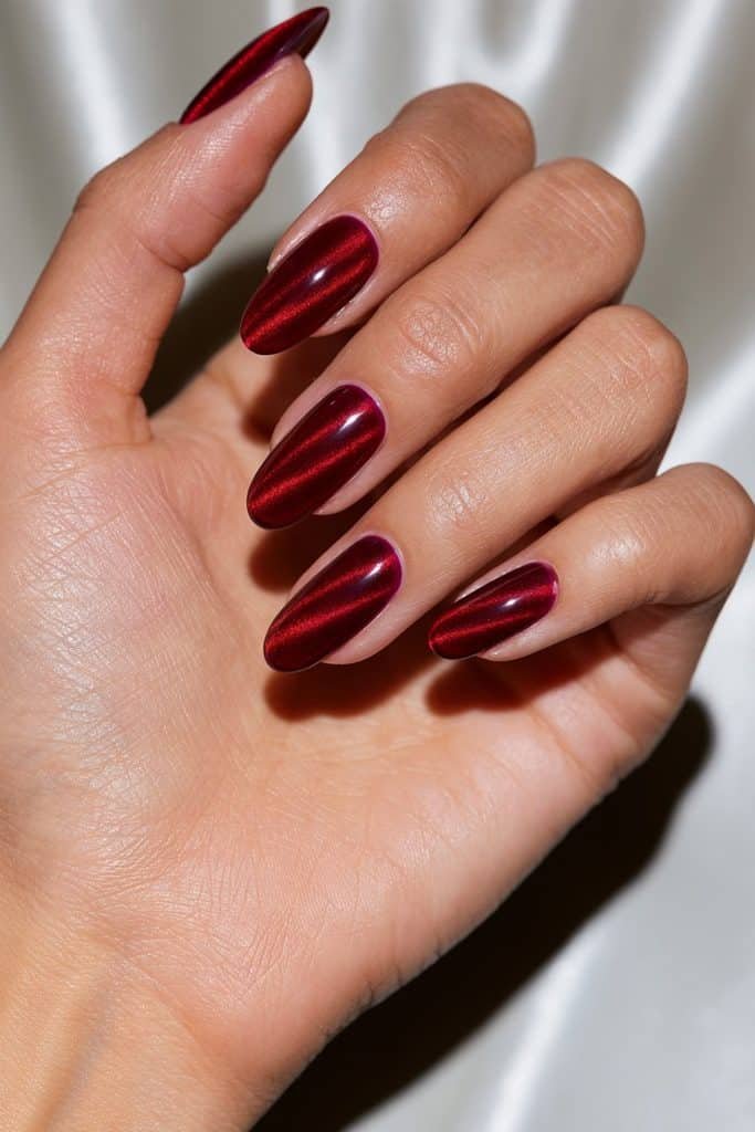 Sheer jelly red cat eye nails with translucent cherry polish, fine silver-red magnetic shimmer, and a glossy glass-like finish.