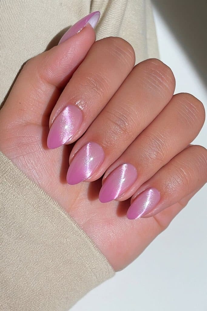 Short almond pink cat-eye nails with sheer rose-pink polish, delicate magnetic streaks, and pearly shimmer