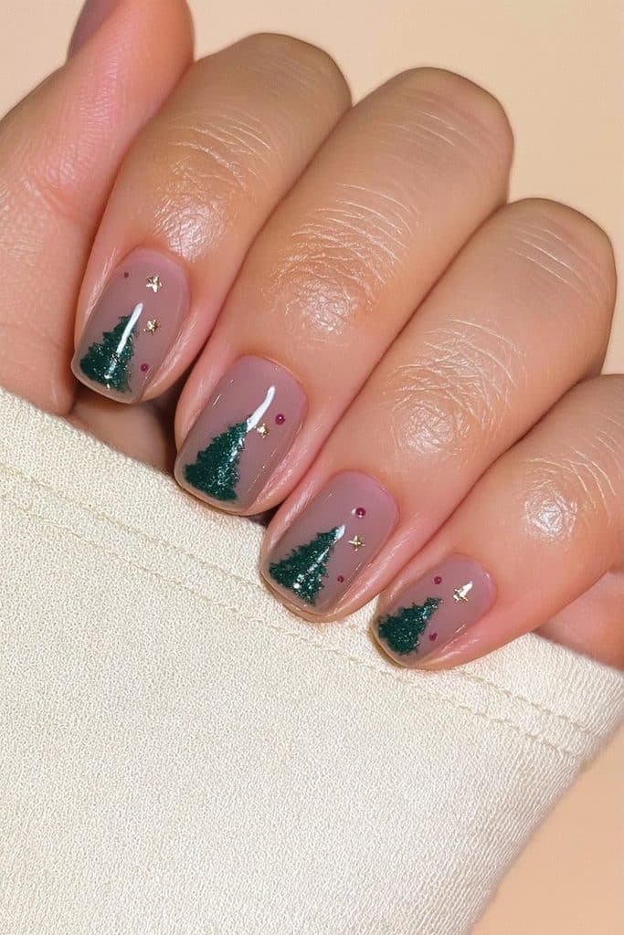Short squoval nails with tiny green Christmas trees, gold stars, and red ornaments
