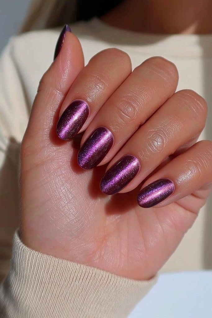 Short oval dark purple cat-eye nails with fine violet magnetic bands and glossy polish