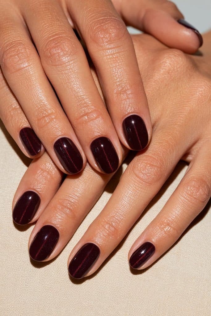 Short oval maroon cat eye nails featuring delicate ruby shimmer and a glossy burgundy magnetic finish.
