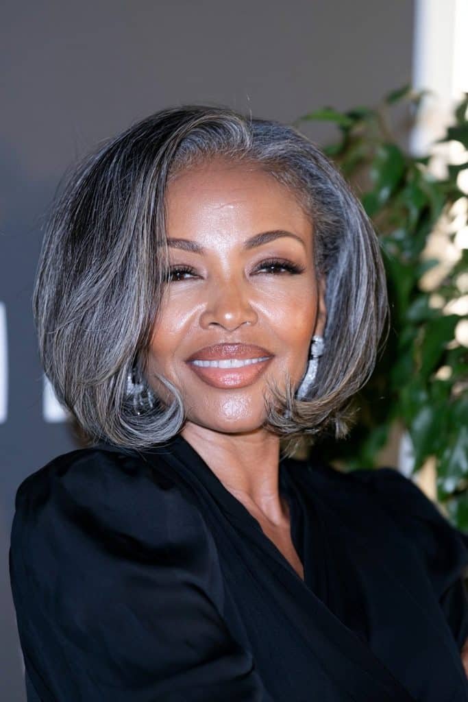 Black woman with a silver flipped bob hairstyle, featuring shimmering silver-gray hair, a sleek finish, and outward-curled ends for a sophisticated look.