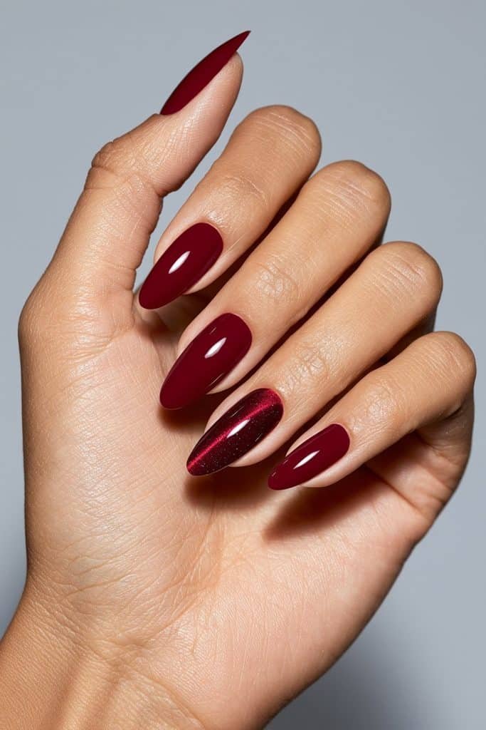 Cherry red manicure with one ruby magnetic cat eye accent nail featuring a luminous stripe and glossy finish.