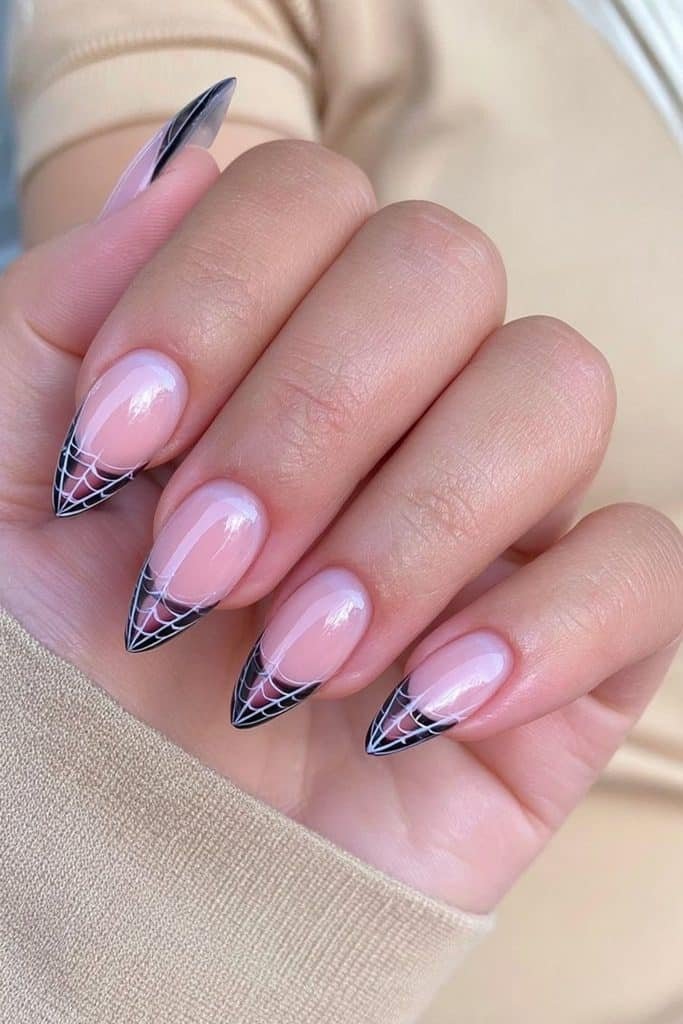 Black French tip nails with delicate white spider web details over a sheer pink base