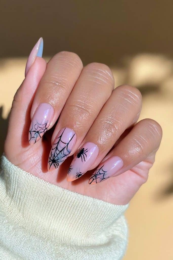 Sheer pink spider web nails with delicate black web lines and tiny spider illustrations