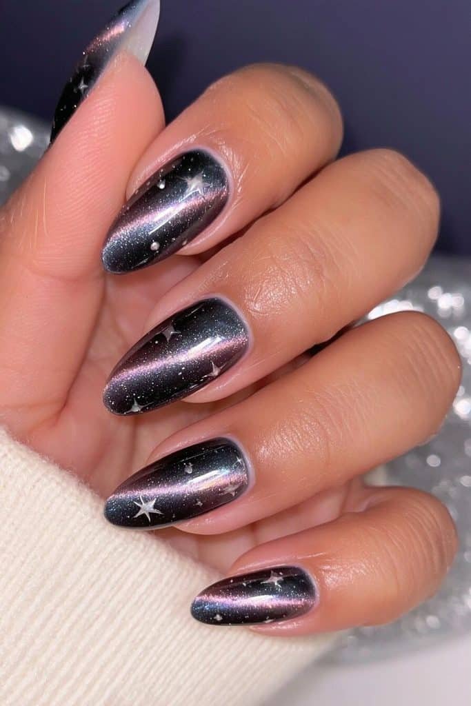 Midnight blue cat-eye nails with sapphire light trails, tiny silver stars, and celestial shimmer