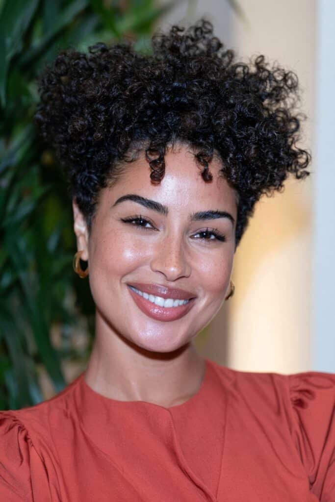 Black woman with a tapered wash-and-go hairstyle showcasing defined natural curls on top and neatly tapered sides.