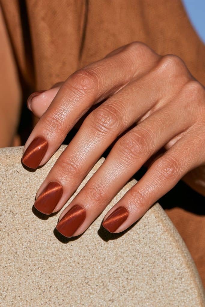 Earthy terracotta cat eye nails with rusty clay-orange color and a glossy magnetic finish.