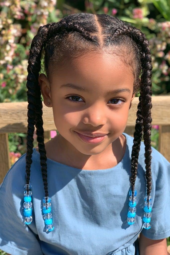 Two neat side braids for a young Black girl, decorated with bright blue and clear beads at the ends.