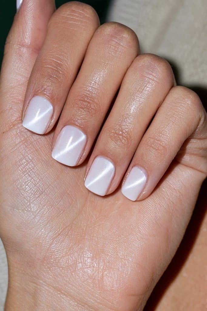 Short squoval white cat eye nails featuring distinct magnetic stripes and glossy polish