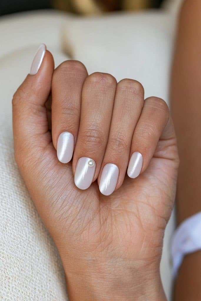 White cat eye nails with glossy magnetic stripes and a tiny pearl charm on the ring finger